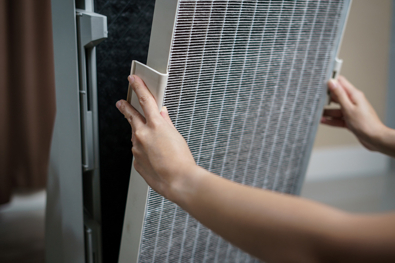 A person installing a hepa filter on an hvac unit.